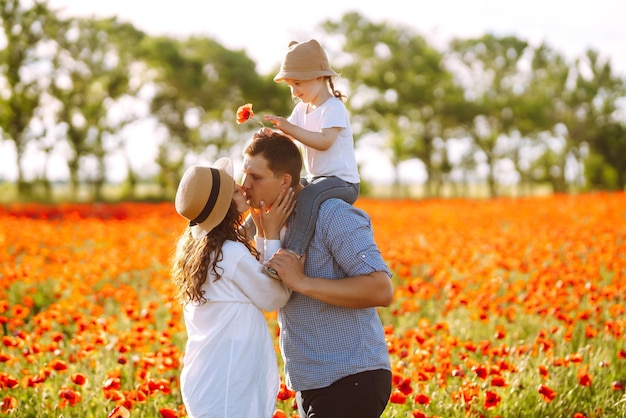 Family with a child walking on a poppy field Mother father little daughter having fun on poppy field