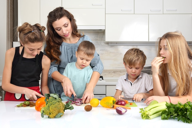 Family with children cut vegetables for cooking