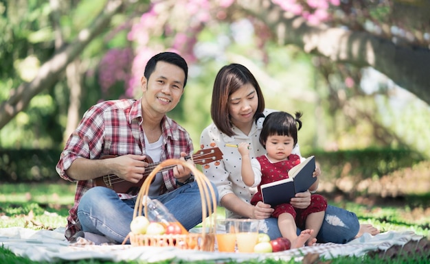 春の庭でピクニックを楽しんでいる子供たちと家族夏の公園で屋外でランチを楽しんでいる親と子供たち庭でウクレレを遊んでいる母と娘