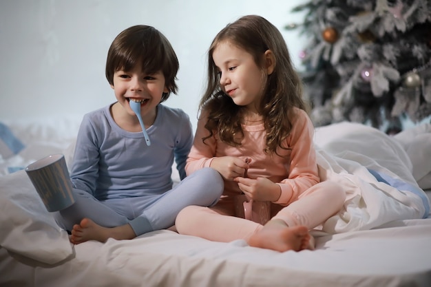 A family with children having fun on the bed under the covers during the Christmas holidays.