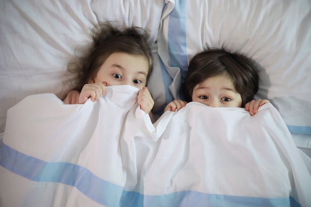 A family with children having fun on the bed under the covers during the Christmas holidays.