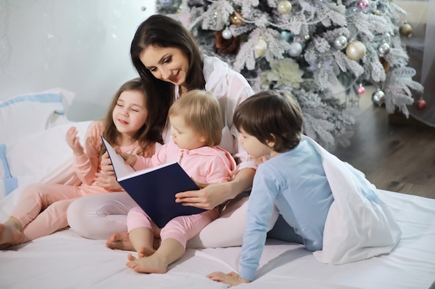 A family with children having fun on the bed under the covers during the Christmas holidays.