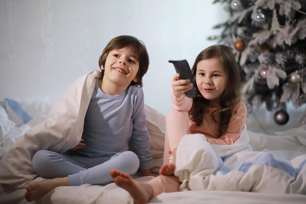 A family with children having fun on the bed under the covers during the Christmas holidays.