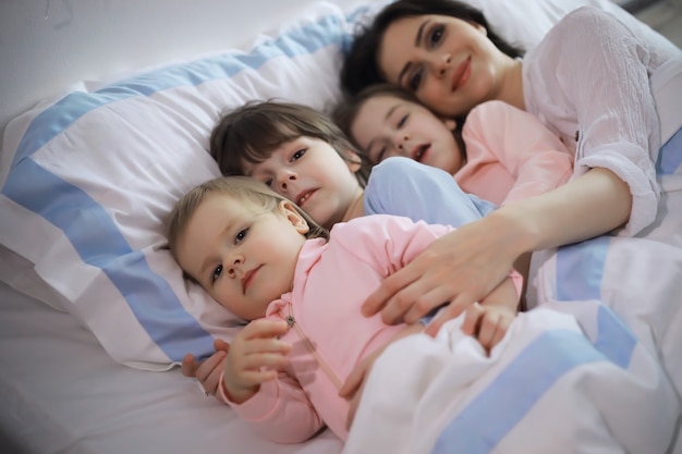 A family with children having fun on the bed under the covers during the Christmas holidays.