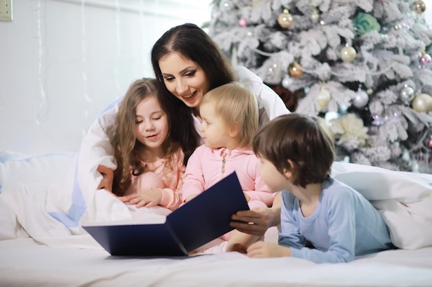 A family with children having fun on the bed under the covers during the Christmas holidays