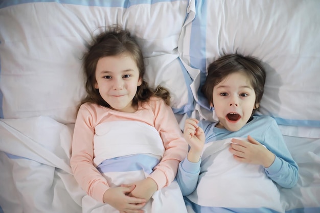 A family with children having fun on the bed under the covers during the Christmas holidays