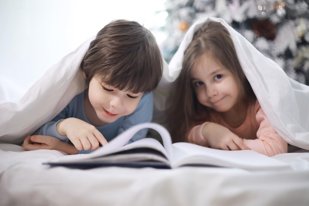 A family with children having fun on the bed under the covers during the Christmas holidays