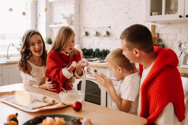 Foto famiglia con bambini che si divertono e ridono mentre si preparano per le vacanze di natale in cucina