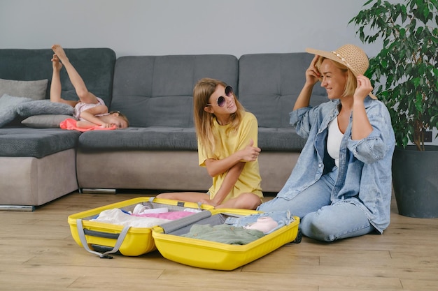 Photo family with children packing yellow suitcase for travel together