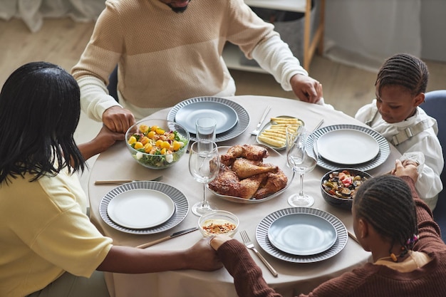 Famiglia con bambini che pregano al tavolo da pranzo