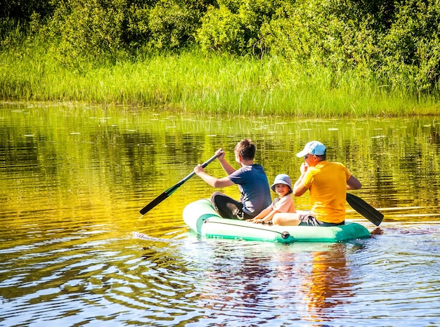 Family with children ride inflatable rubber boat on the river .