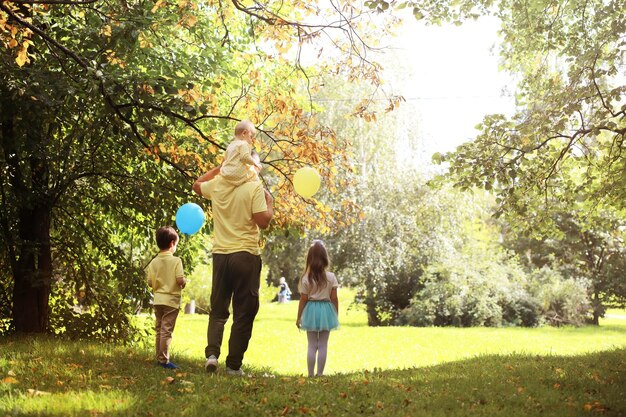 サマーパークを散歩する子供連れの家族。公園で秋が近づいています。家族。秋。幸せ。