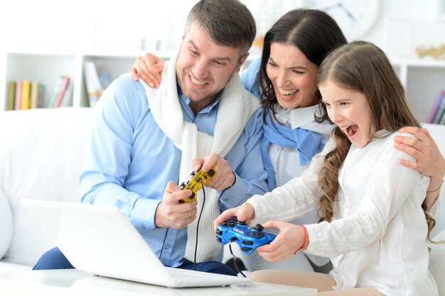 Photo family with daughter playing a computer game