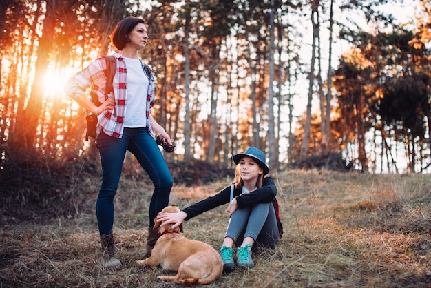 Family with dog resting in forest during sunset