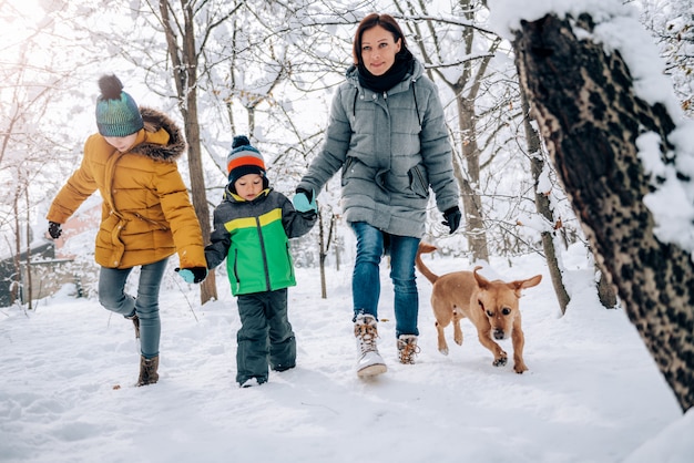 Famiglia con cane che cammina su una neve fresca