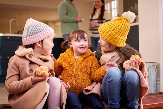 La famiglia con la figlia di sindrome di down si prepara per andare a camminare insieme per l'autunno o l'inverno