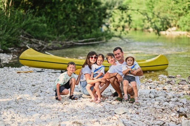 Family with four kids against canoe in rocky shore of a calm river in Triglav National Park Slovenia