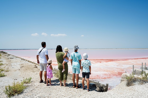 Family with four kids against red salt lake in Saline Margherita di Savoia of Italy