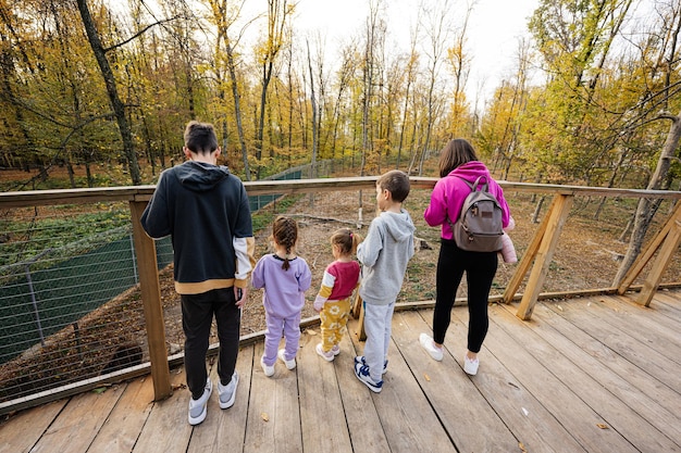 Family with four kids looking at wild animals from wooden bridge