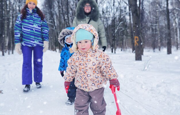 Family with kids in winter park on snowy weekend