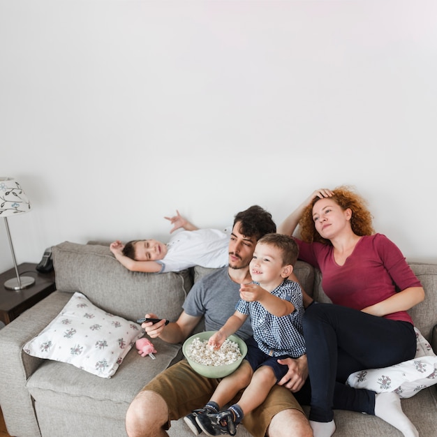 Famiglia con popcorn guardando la televisione a casa