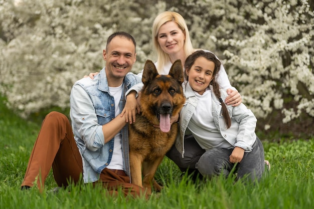 Famiglia con bambino piccolo e cane all'aperto nel frutteto in primavera.