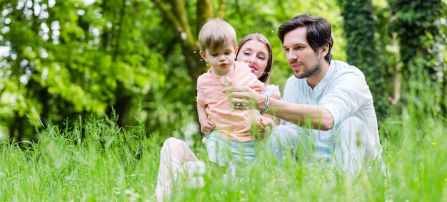 Famiglia con figlio sul prato che soffia fiore di tarassaco