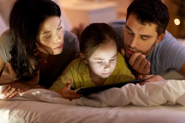 Foto famiglia con tablet sul letto di notte a casa