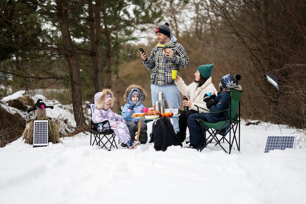 Family with three children in winter forest spending time together on a picnic