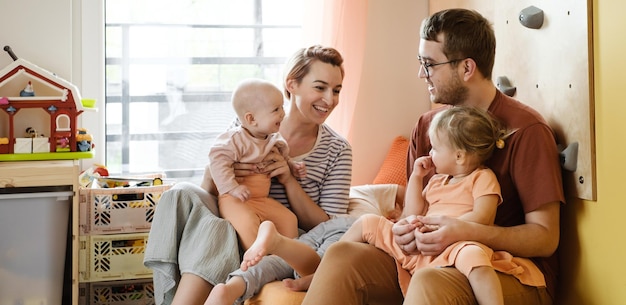 Famiglia con due bambini che giocano a casa sul pavimento