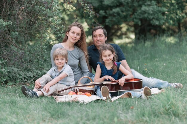 Family with two children resting on the sunny lawn in the summer park