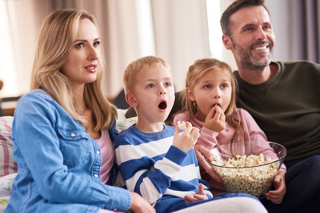 Famiglia con due bambini che guardano la tv in soggiorno