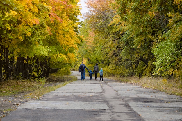 Family with two sons are walking in the autumn park.