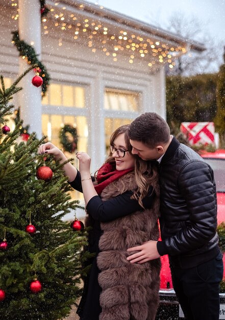 family, x-mas, winter holidays and people concept - happy couple decorating christmas tree