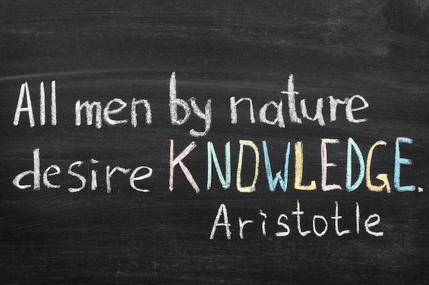 Famous Aristotle quote "All men by nature desire knowledge" handwritten on blackboard