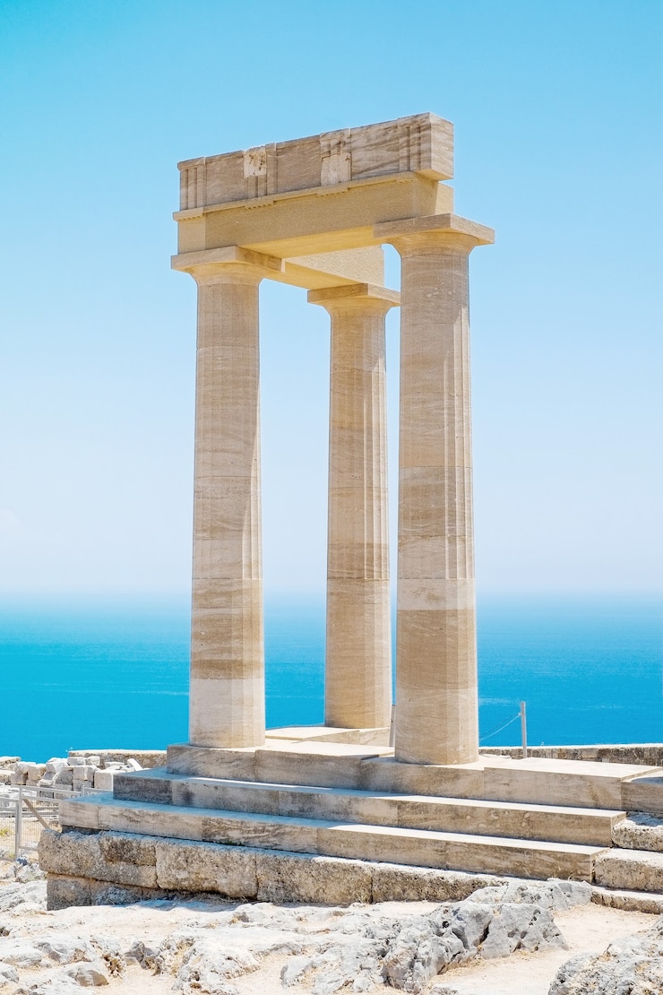 ギリシャのリンドスアクロポリスロードスアテナ寺院の澄んだ青い空と海を背景にした有名なギリシャ神殿の柱