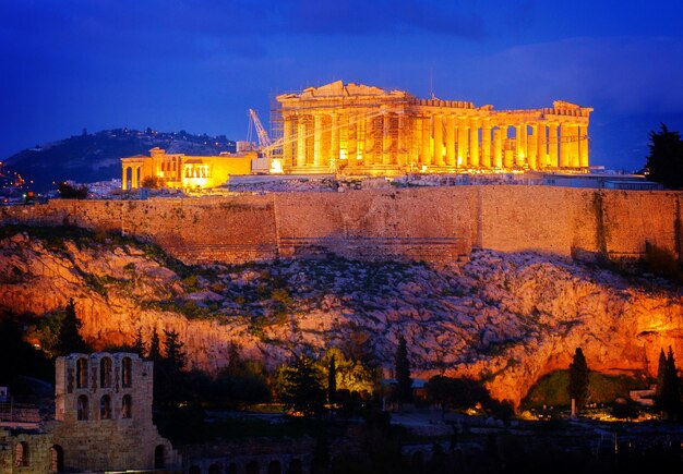 Photo famous skyline of athens with acropolis hill and pathenon illuminated at night athens greece retro toned