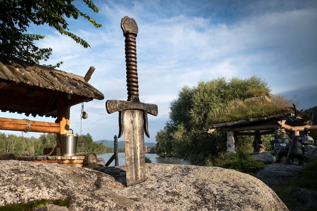 Photo famous sword excalibur of king arthur stuck in rock edged weapons from the legend pro king arthur