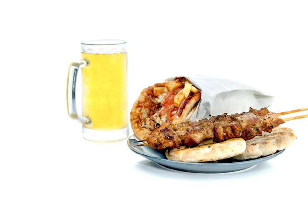 Famous traditional Greek snacks grilled soufflaki lie on a gray plate and a glass of beer closeup on a white background