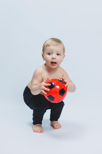 子供のためのサッカースポーツの白い背景の初心者に隔離された彼の手でサッカーボールを保持しているファンの少年小さな運動選手