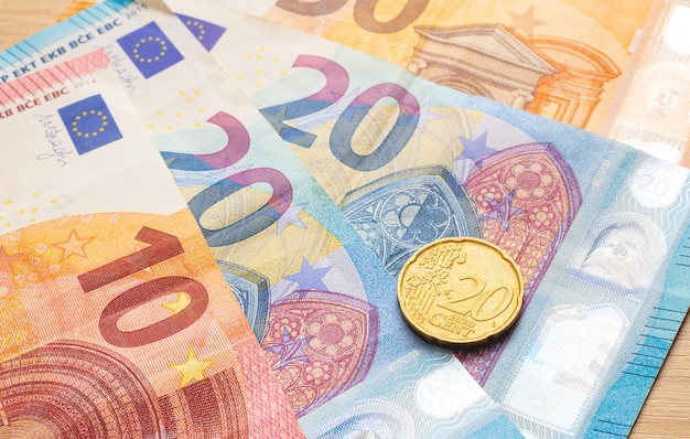 Photo fan shaped euro banknotes on the table and a twentycent euro coin