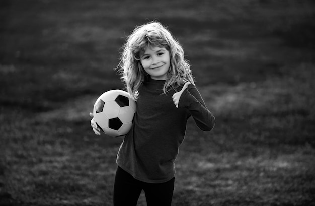 Фан-спорт мальчик игрок держит футбольный мяч футбол ребенок играет в футбол показывает палец вверх знак успеха