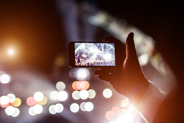 Поклонник фотографирует концерт на фестивале с помощью смартфона