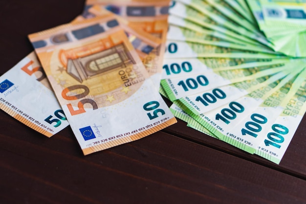 Fan van papiergeld honderd euro bankbiljetten en hoop van vijftig euro op houten tafel Selectieve focus