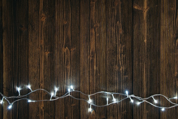 Photo fancy blinker light bulbs or garlands and wreath on wood