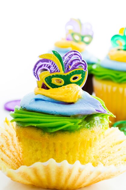 Fancy cupcakes decorated with leaf and mask for Mardi Gras party.