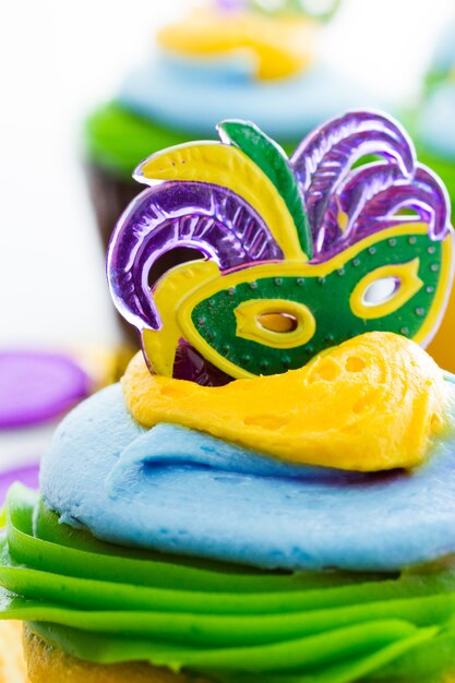 Fancy cupcakes decorated with leaf and mask for Mardi Gras party.