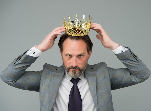 Fancy himself as king. Bearded man wear king crown. Big boss. Leader and leadership. Businessman or business person. King of business. Kings ambitions. Pageant of coronation. Egoism and selfishness.