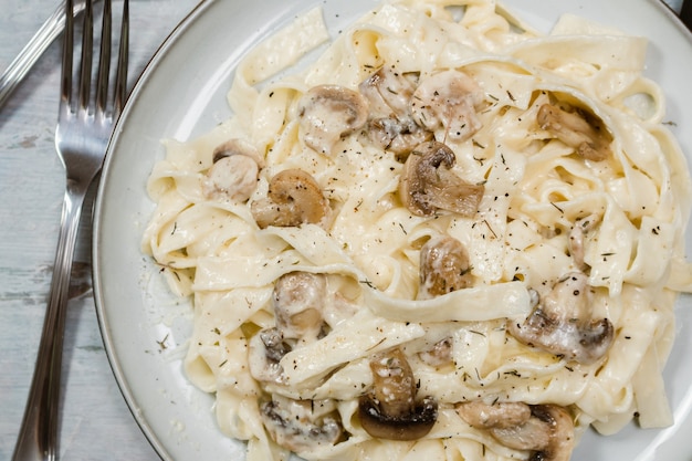 Fancy organic fetuccine pasta with creamy alfredo mushroom sauce. Rustic surface.