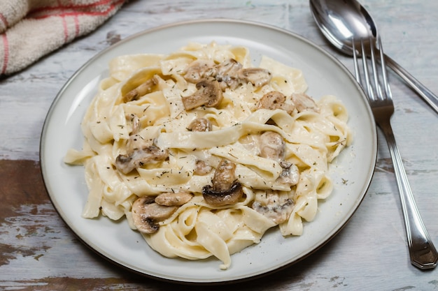 Fancy organic fetuccine pasta with creamy alfredo mushroom sauce. Rustic surface.
